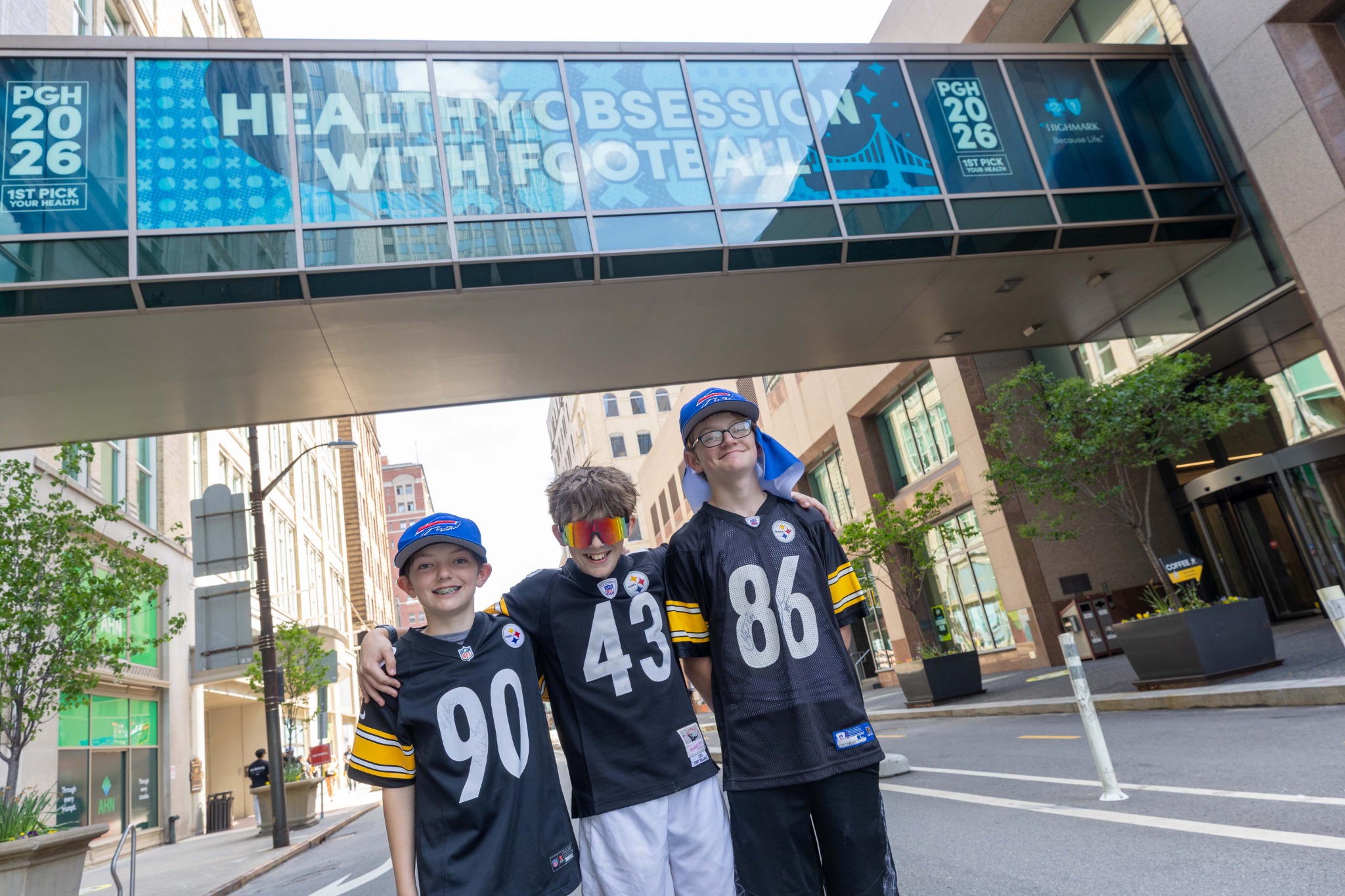 Family of football fans beneath the Highmark skybridge graphics