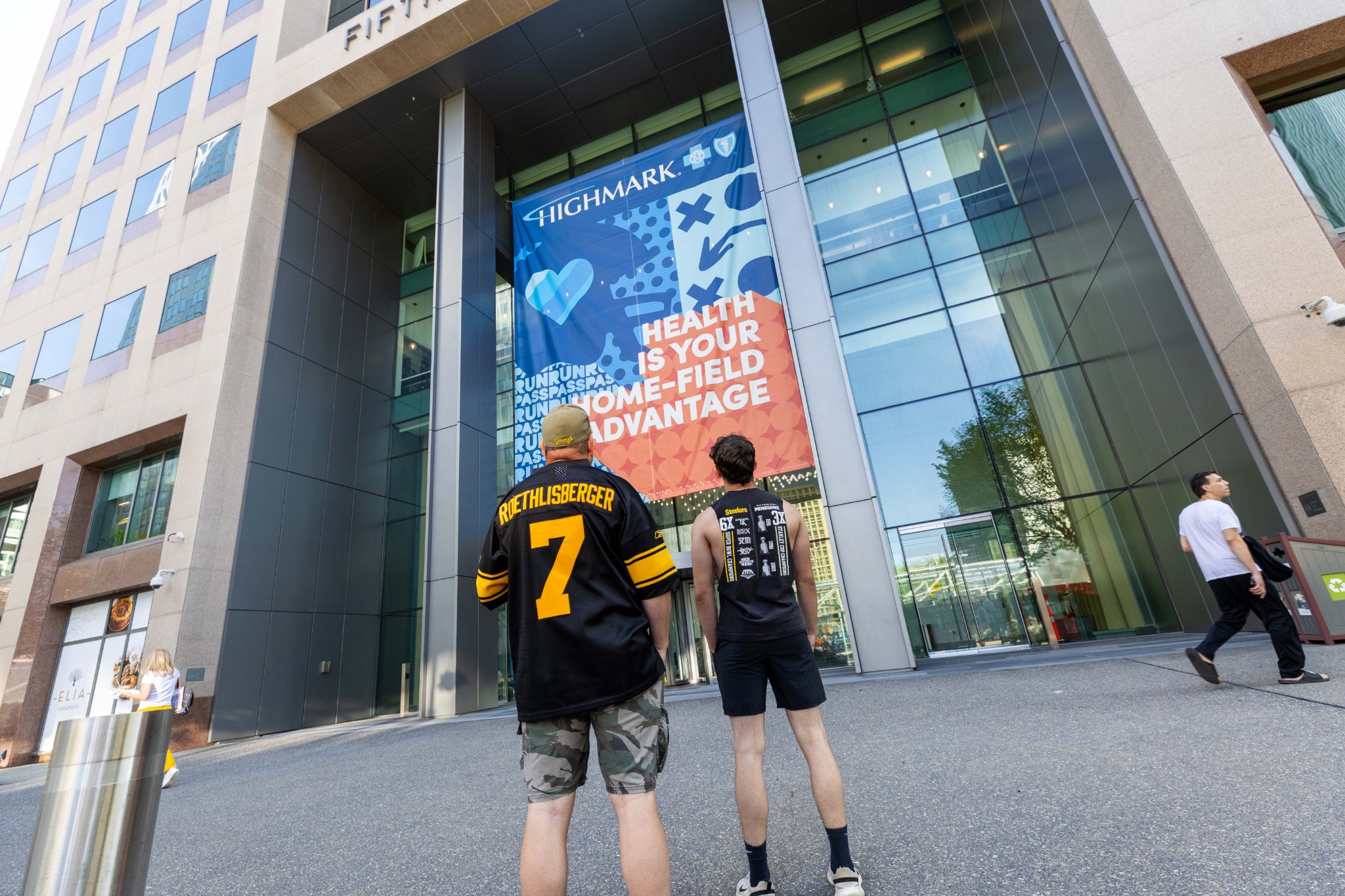 Football fans looking up at the Highmark headquarters graphics