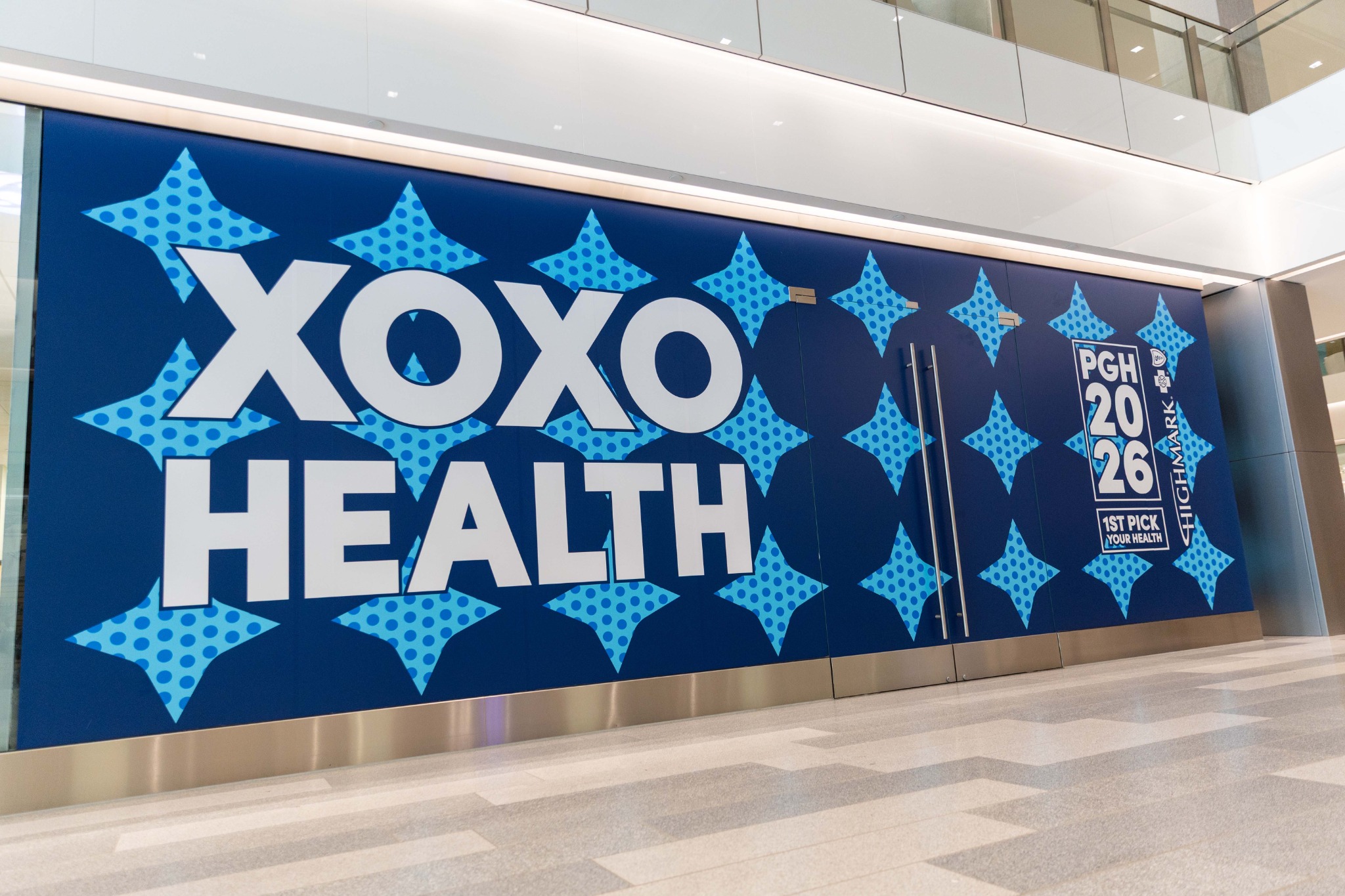 XOXO Health graphics covering the interior wall and doors at Highmark’s Pittsburgh headquarters for the 2026 NFL Draft